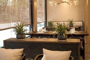 Un comedor moderno con una mesa de madera, plantas en macetas y un banco con cojines.