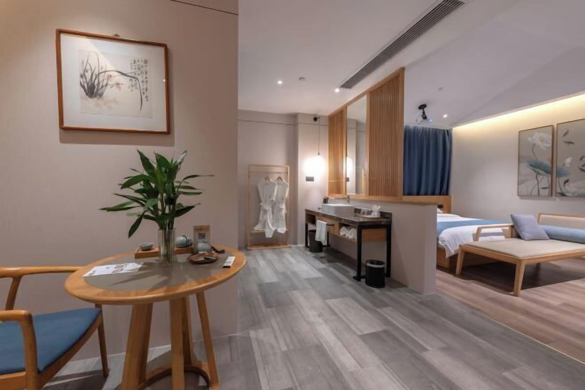 A hotel room with a bed, a sitting area, a bathroom, and a dining area.