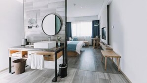 Una habitación de hotel moderna con un espejo grande, un lavamanos, una cama, un televisor y una mesita.