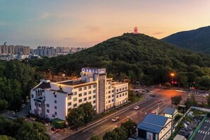 A hotel with multiple floors, surrounded by greenery and a hilly landscape. - Yi Yuan Hotel (Wuxi)