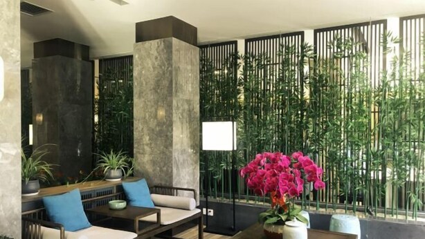 Un vestíbulo moderno con zona de estar, una mesa de madera y un arreglo floral decorativo.