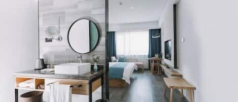 A modern hotel room with a large mirror, a sink, a bedside table, a bed, a TV, and a window with curtains.
