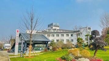 A building with a modern design, surrounded by a well-maintained garden with various plants and flowers.