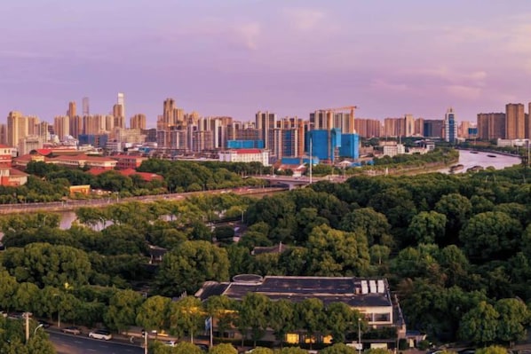 A cityscape with a river, dense greenery, and high-rise buildings.