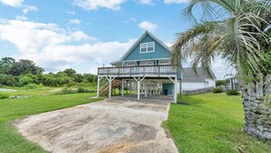 A house with a covered porch, a front yard, and a palm tree.
