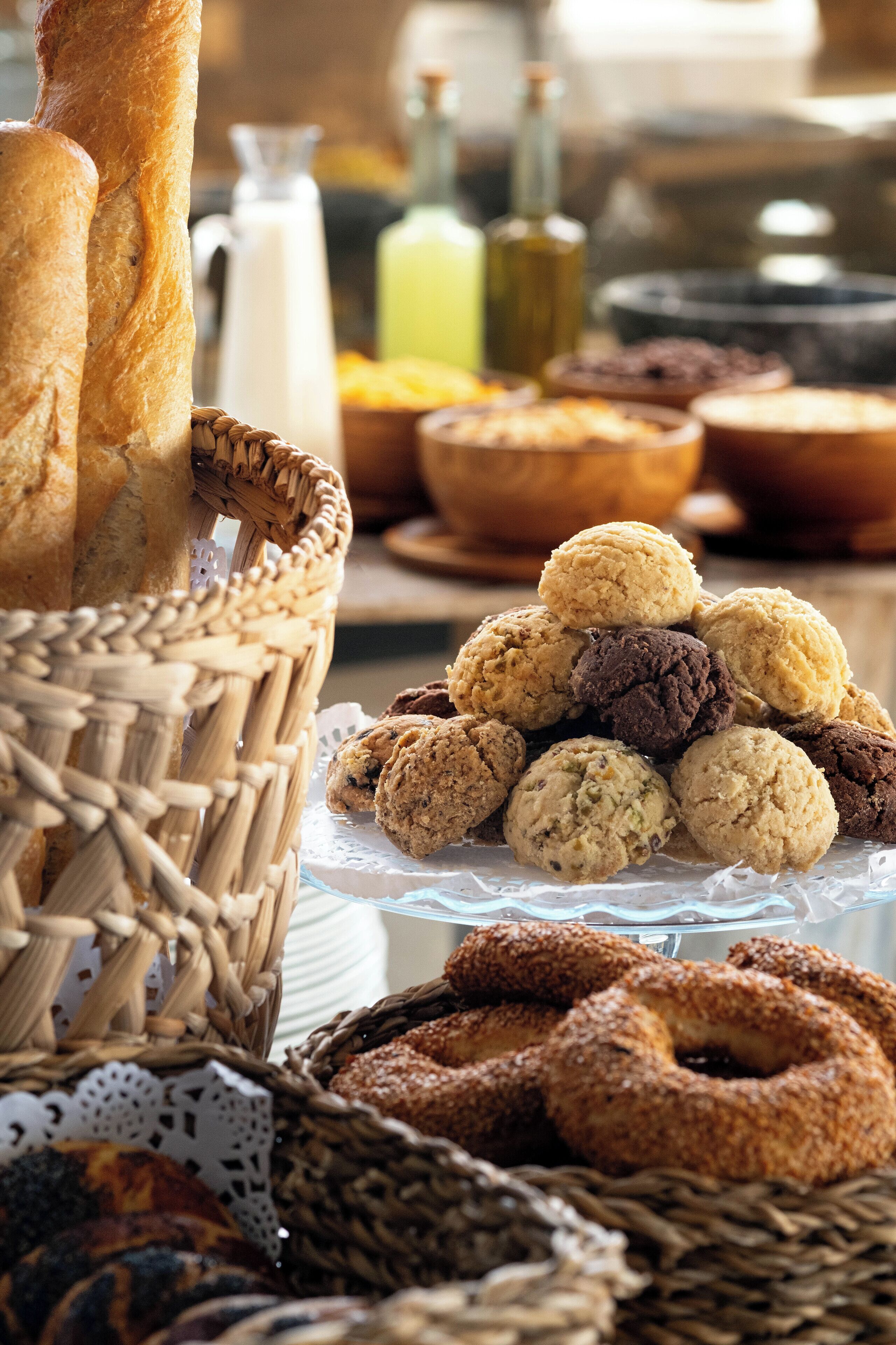 A variety of baked goods including bread, cookies, and pastries displayed in baskets and on a glass stand.