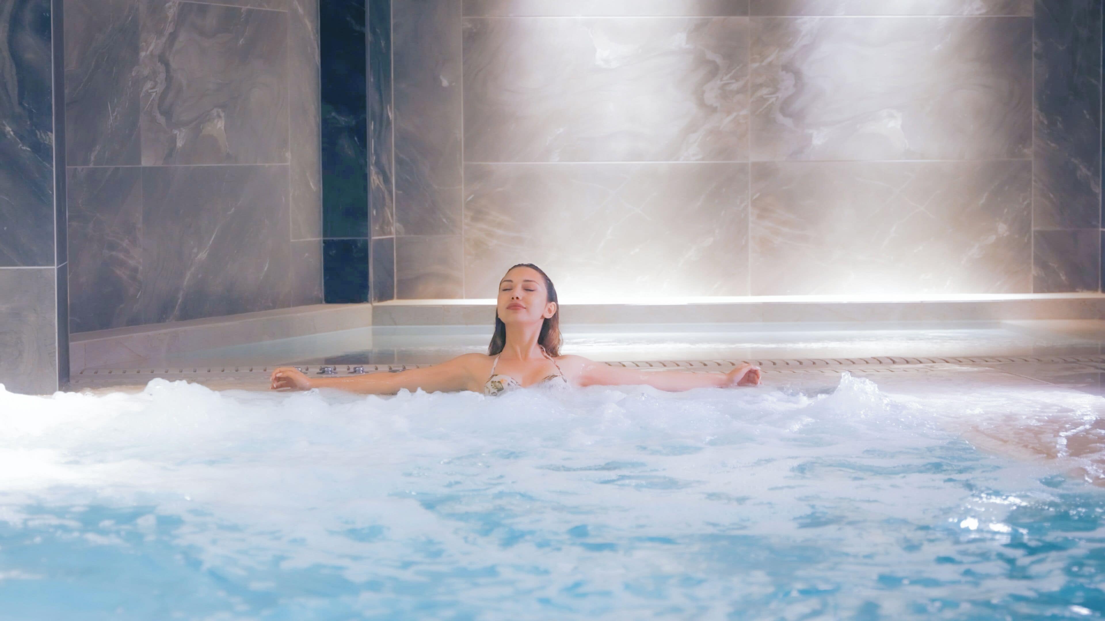 A person relaxing in a hot tub with steam rising from the water.