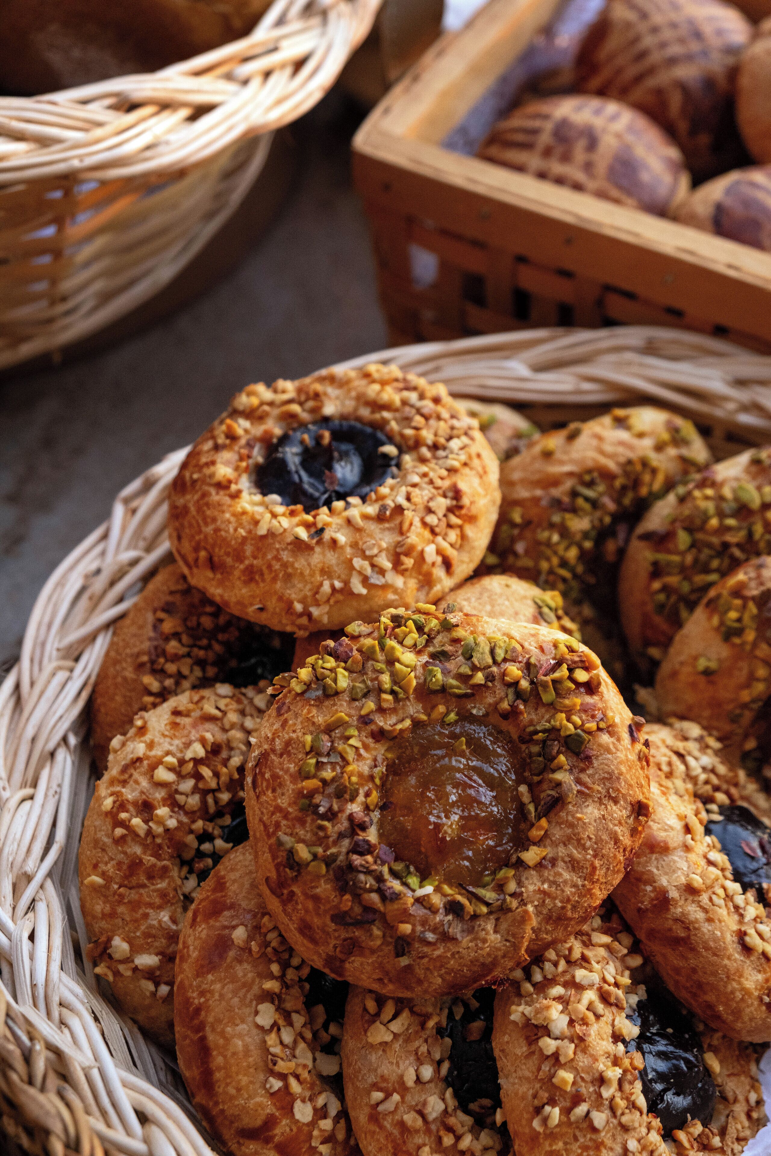 Un panier rempli de viennoiseries aux noix et à la garniture foncée, posé sur une table.