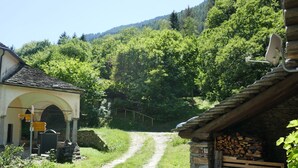 A rural path leading to a traditional stone building with a sloped roof and a satellite dish. - Rustico Ingrid (MVA338) by Interhome (Malvaglia)