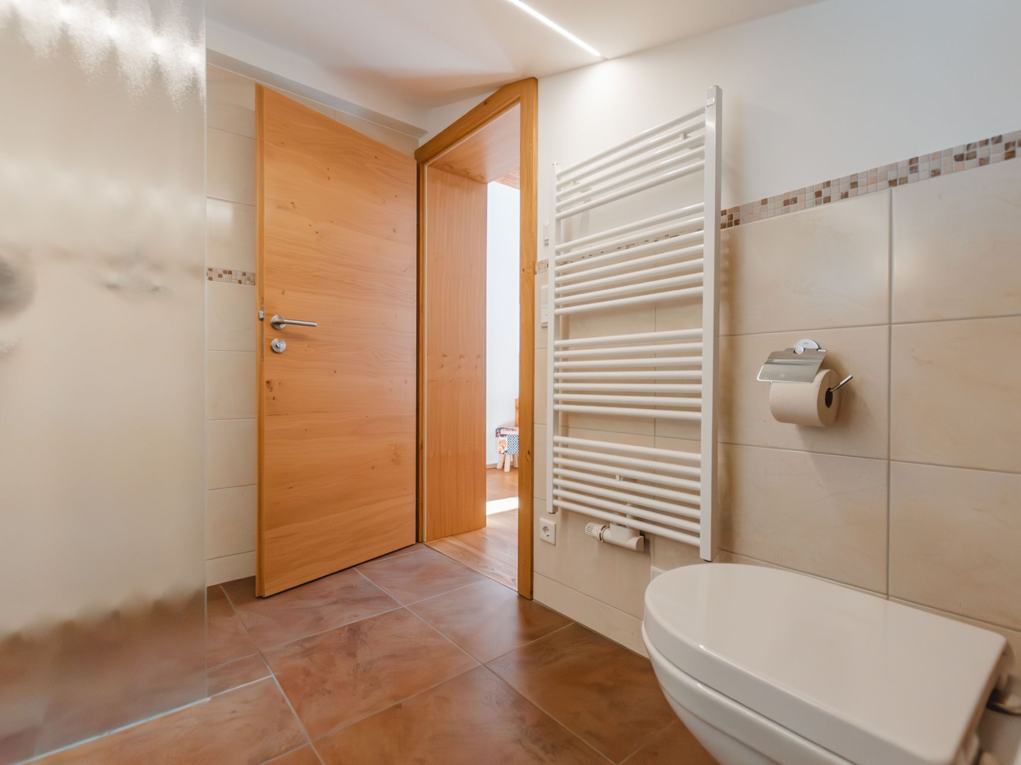 Ein Badezimmer mit Toilette, Handtuchhalter und Holztür.