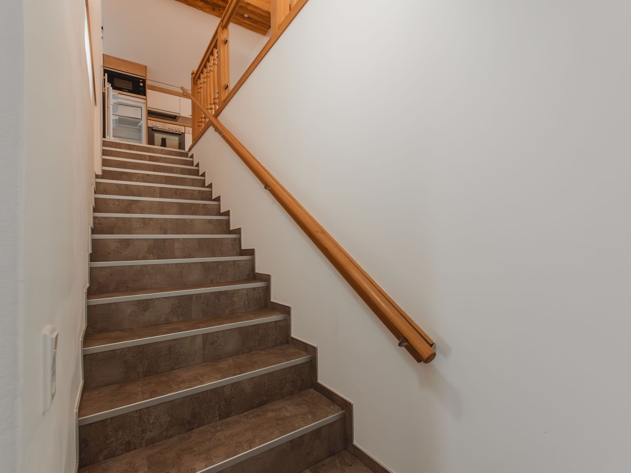 Eine Treppe mit Holzhandläufen und einer Küche im Hintergrund.