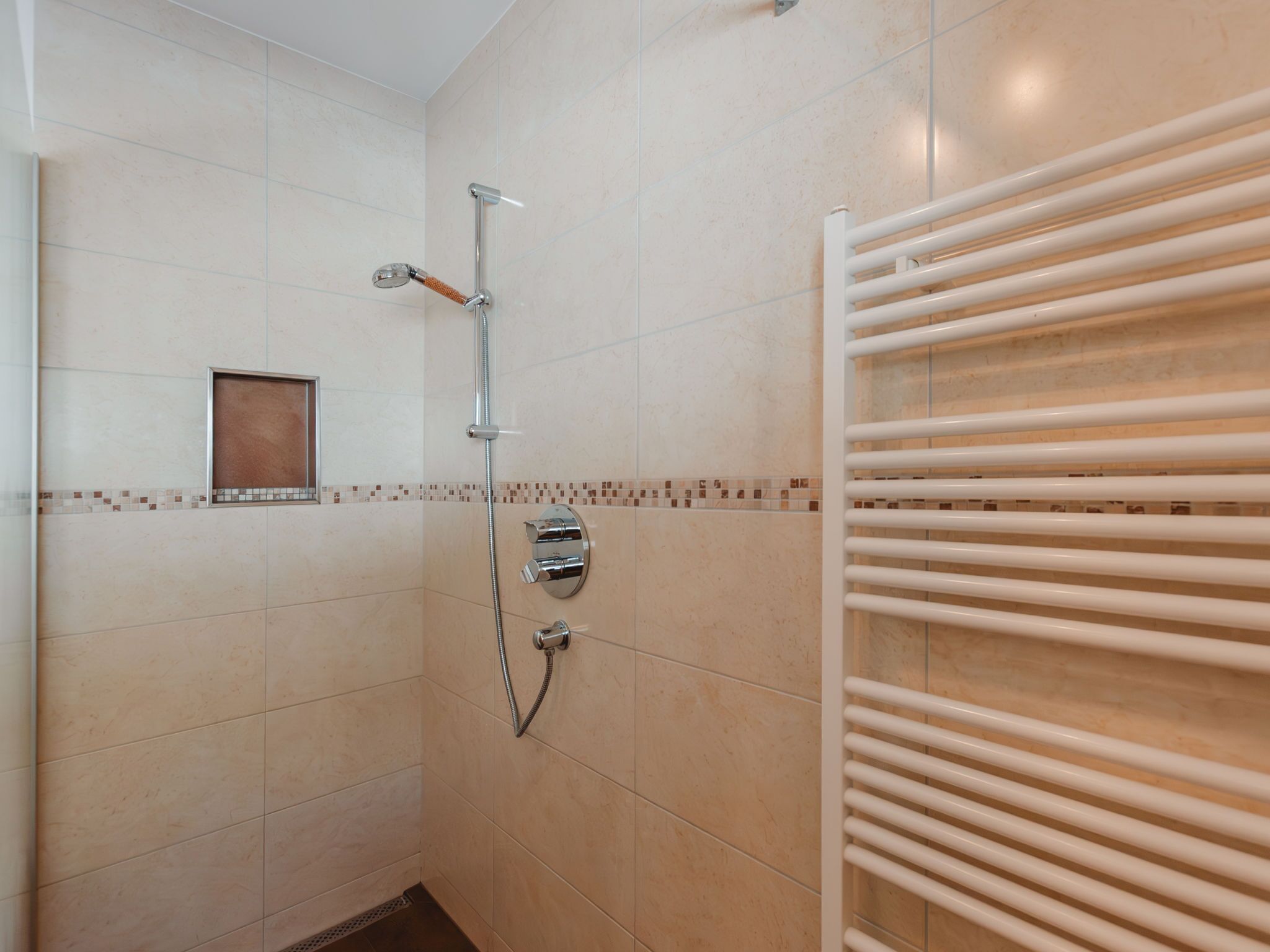 A bathroom with a shower, a towel rack, and a small window.