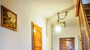 Un couloir avec des portes en bois, un banc, une cheminée et un lustre.