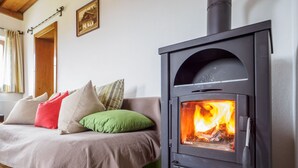 Une pièce confortable avec un lit, un canapé et un poêle à bois.