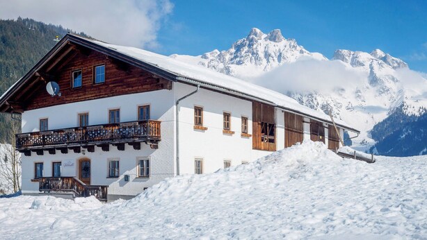Un bâtiment blanc doté de balcons en bois, avec une chaîne de montagnes en arrière-plan.