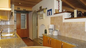 Cozinha com bancadas de granito, armários de madeira, cafeteira e pia.