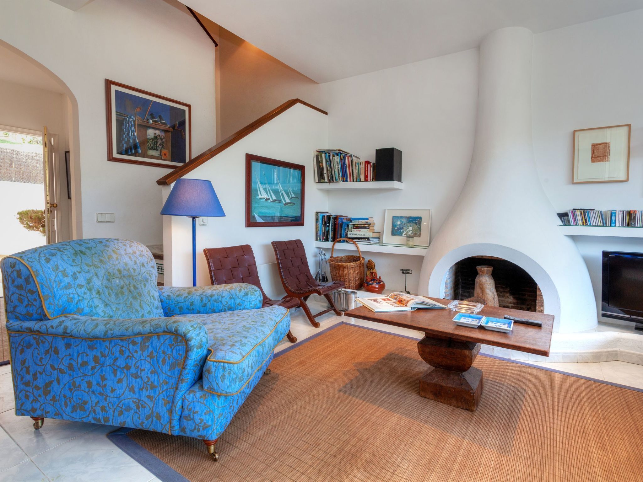 A living room with a blue patterned sofa, a wooden coffee table, and a fireplace.