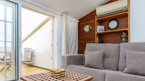 A living room with a grey sofa, a wooden table with a basket of fruit, and a sliding glass door leading to an outdoor area. - Port L'escala by Interhome (L'Escala)
