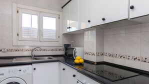 A compact kitchen with white cabinets, a washing machine, a coffee maker, and a toaster. - Riells Park by Interhome (L'Escala)