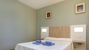 A hotel room with a bed, two nightstands, a wooden headboard, and two wall-mounted lights. - Del Lago by Interhome (L'Escala)