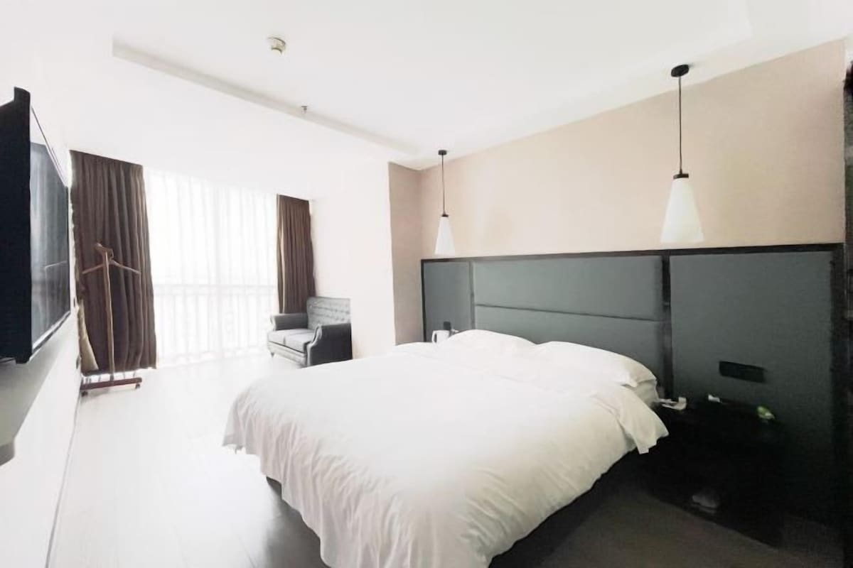 A modern hotel room with a large bed, a desk, and a TV.