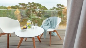 A balcony with two white chairs, a small table, a bowl of fruit, a pitcher of water, and two glasses. - Mariandl am Meer by Interhome (Ostseebad Binz)