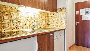 Uma cozinha com painel de azulejos, pia de aço inoxidável e armários de madeira.