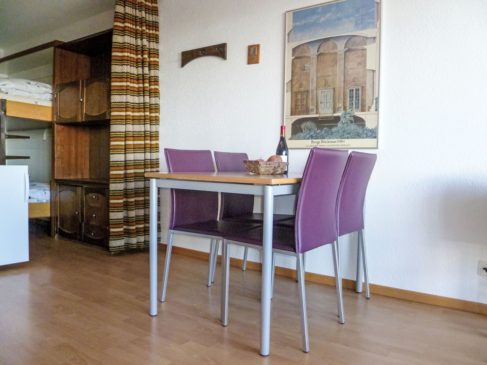 A dining area with a table and chairs, a bunk bed, and a painting on the wall.