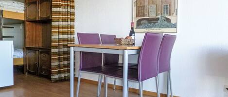 A dining area with a table and chairs, a bunk bed, and a painting on the wall.