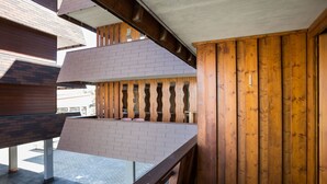 Een balkon met een houten hekwerk en bakstenen muur, uitkijkend op een geplaveid gebied.