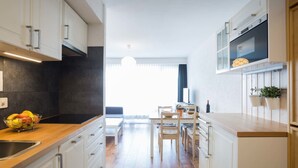 A modern kitchen with white cabinets, a wooden countertop, and a dining area with a table and chairs. - Greppon 107 by Interhome (Thyon-Les Collons)