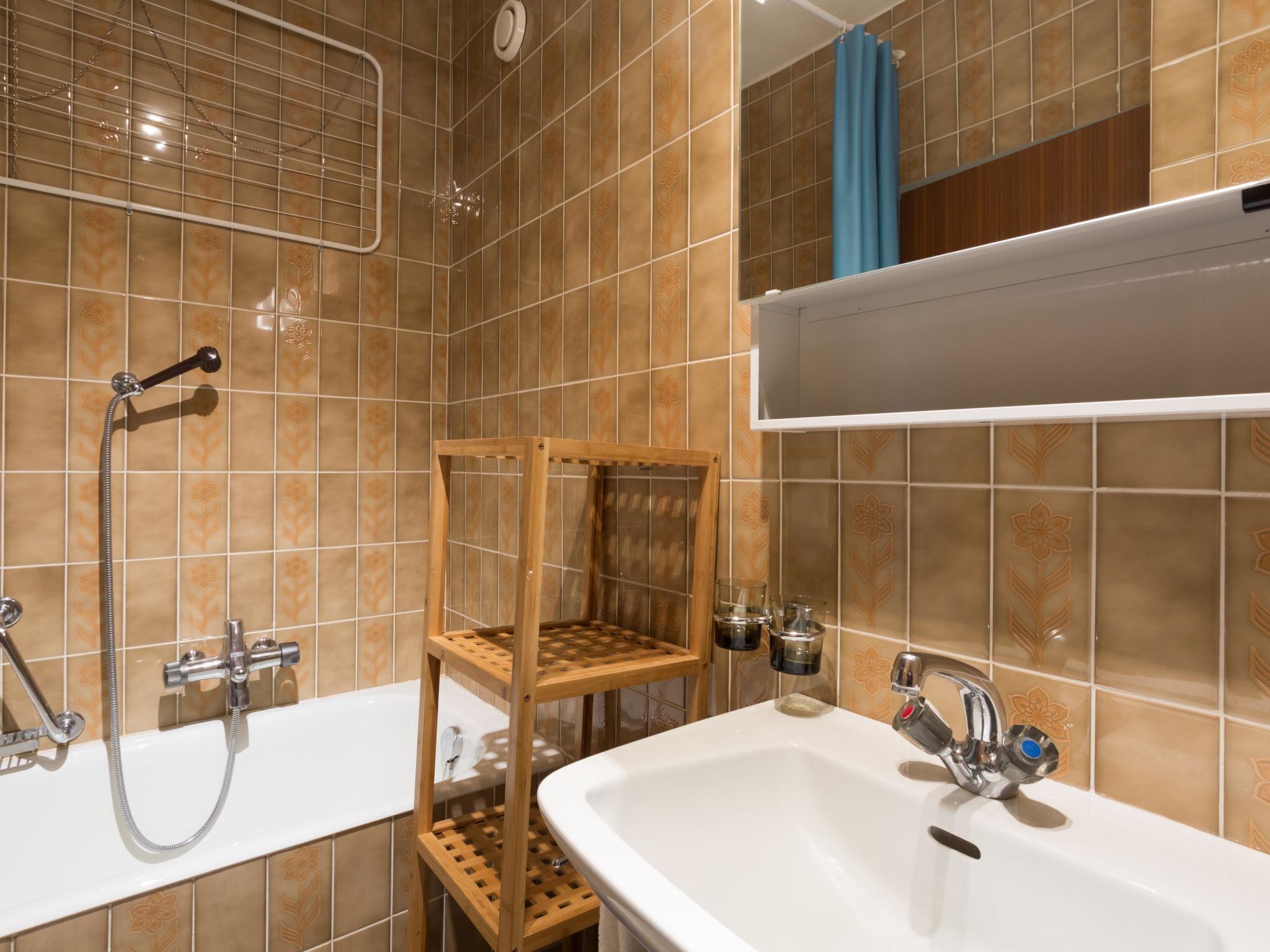 Un bany amb dutxa, un lavabo i una prestatgeria de fusta.