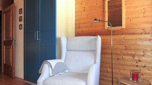 A room with a white armchair, a blue wardrobe, a floor lamp, and a small table with a candle. - Fischerhütte by Interhome (Stein an der Enns)