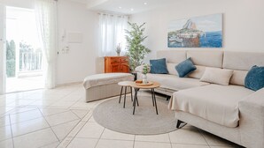 A modern living room with a beige sofa, a round coffee table, and a painting of a coastal scene. - Heringklee by Interhome (Calpe/Calp)