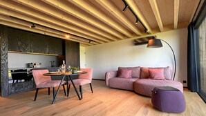 A modern living room with a wooden ceiling, a pink sofa, a round table with chairs, and a purple ottoman. - Romantic Stay with Views (Enneille)