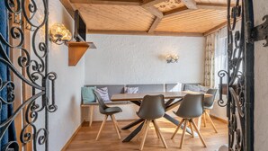 A dining area with a wooden table and chairs, a bench with cushions, and decorative wall sconces. - Apartment Nadine by Interhome (Sölden)