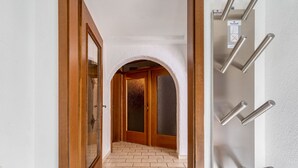 A hallway with a wooden door, a glass door, and a tiled floor. - Apartment Nadine by Interhome (Sölden)