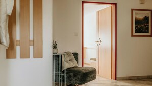 A room with a dark grey sofa, a small side table with a plant, a door leading to another room, and a framed picture on the wall.