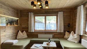 A cozy cabin room with wooden walls, a large window, and a seating area with cushions. - Eberharter by Interhome (Zell am Ziller)