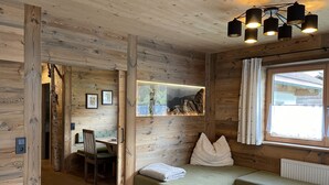 A cozy wooden cabin interior with a bench, a table, and a window overlooking a mountain view. - Eberharter by Interhome (Zell am Ziller)
