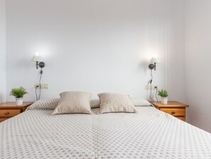 Cozy retreat with a patterned duvet and two bedside tables, each with a small potted plant.