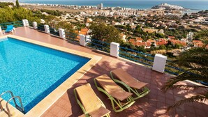 Une piscine dotée de chaises longues et offrant une vue sur le paysage urbain de la côte.