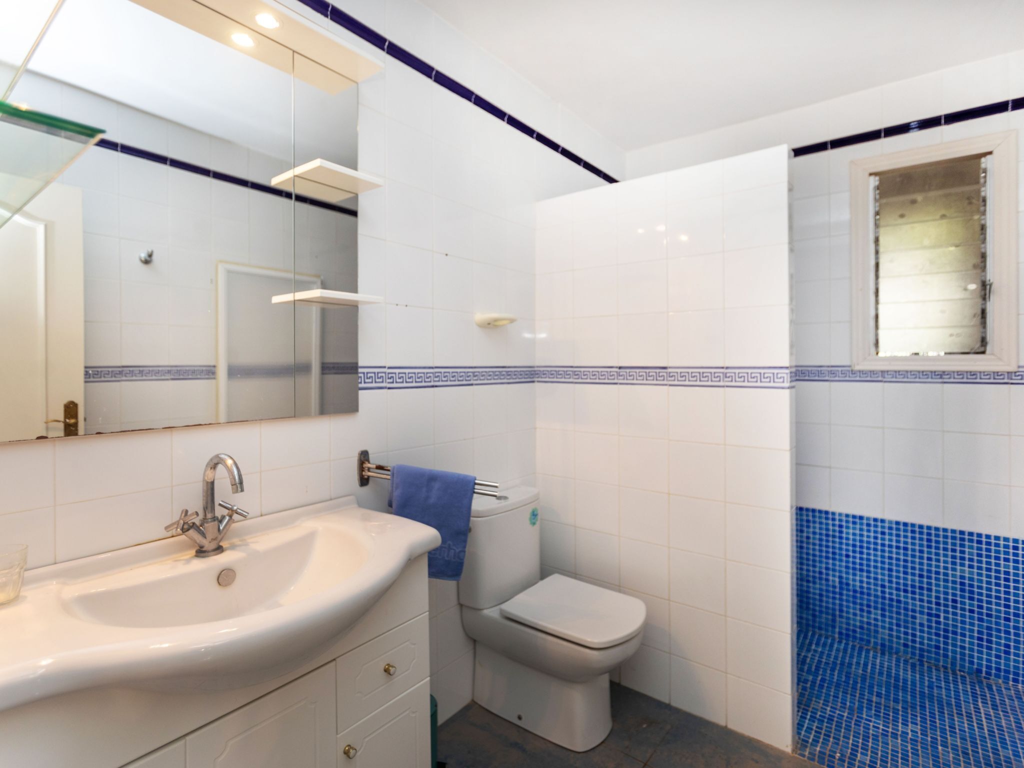 A bathroom with a sink, mirror, toilet, and shower.