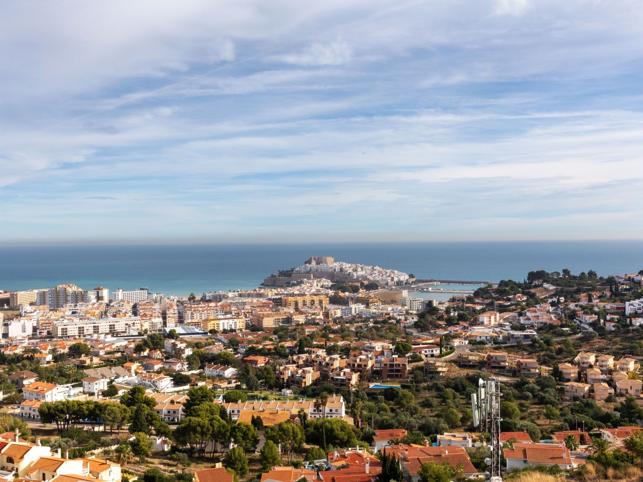 A coastal cityscape with a prominent hilltop fortress, dense residential areas, and a clear view of the sea.