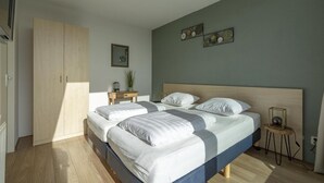 Een moderne slaapkamer met een groot bed, een kledingkast en een nachtkastje met een lamp.