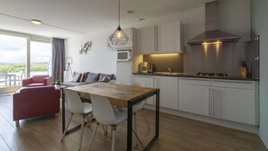 Een moderne keuken met een eethoek, grote ramen en uitzicht op de omgeving.