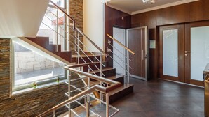 Un interior moderno con una escalera de madera, una pared de acento de piedra y vistas a través de un gran ventanal.