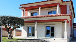 Un edificio de dos pisos con fachada roja y blanca, ventanas amplias y techo de tejas.