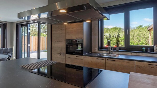 A modern kitchen with a large island, stainless steel appliances, and a view of the outdoors. - Villa near North Holland Beach with Jacuzzi (Julianadorp aan Zee)