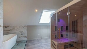 A modern bathroom with a skylight, a bathtub, and a glass-enclosed shower area. - Villa near North Holland Beach with Jacuzzi (Julianadorp aan Zee)